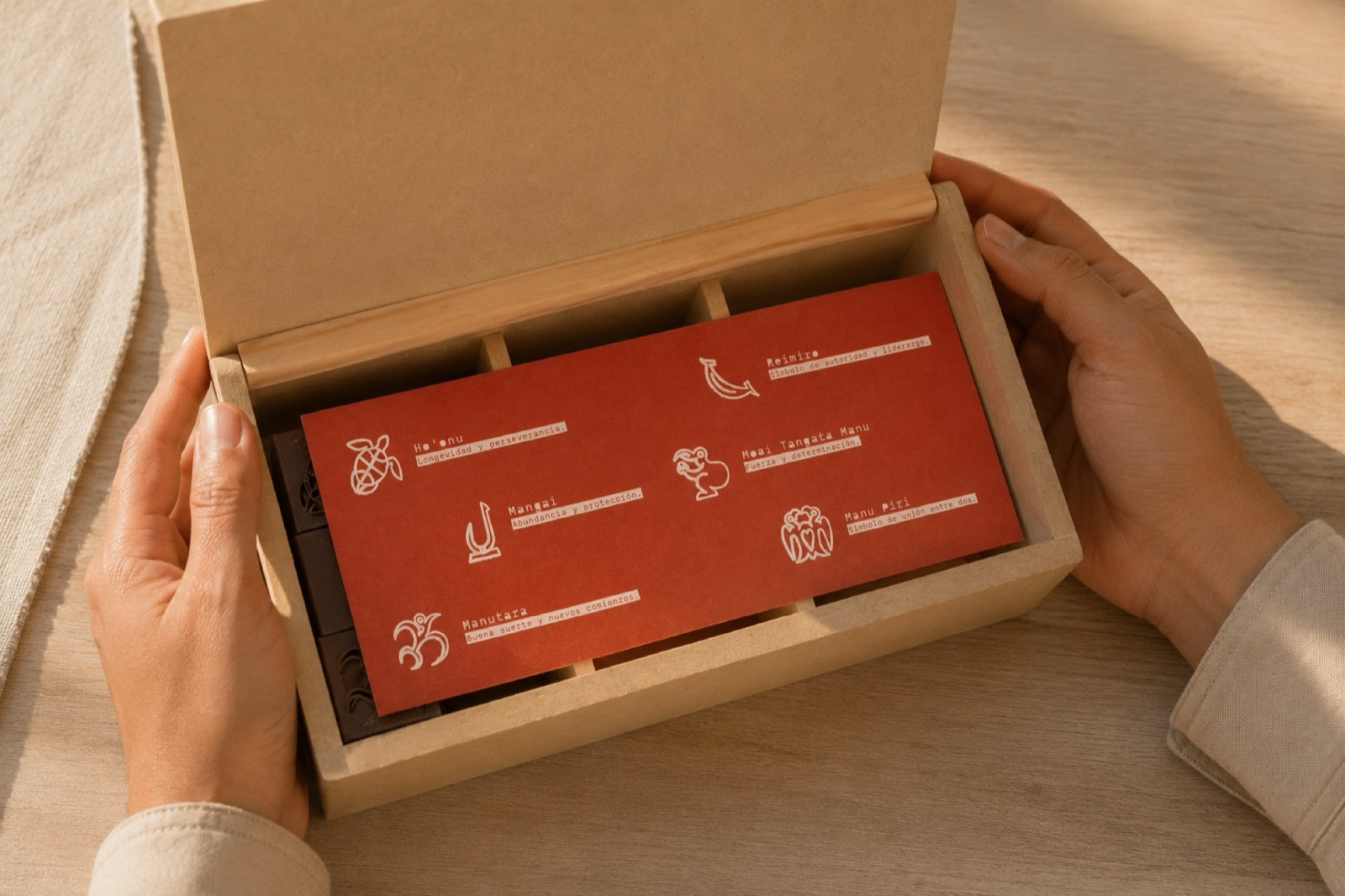 Manos abriendo la caja de Tātohi con la bandeja naranja de instrucciones