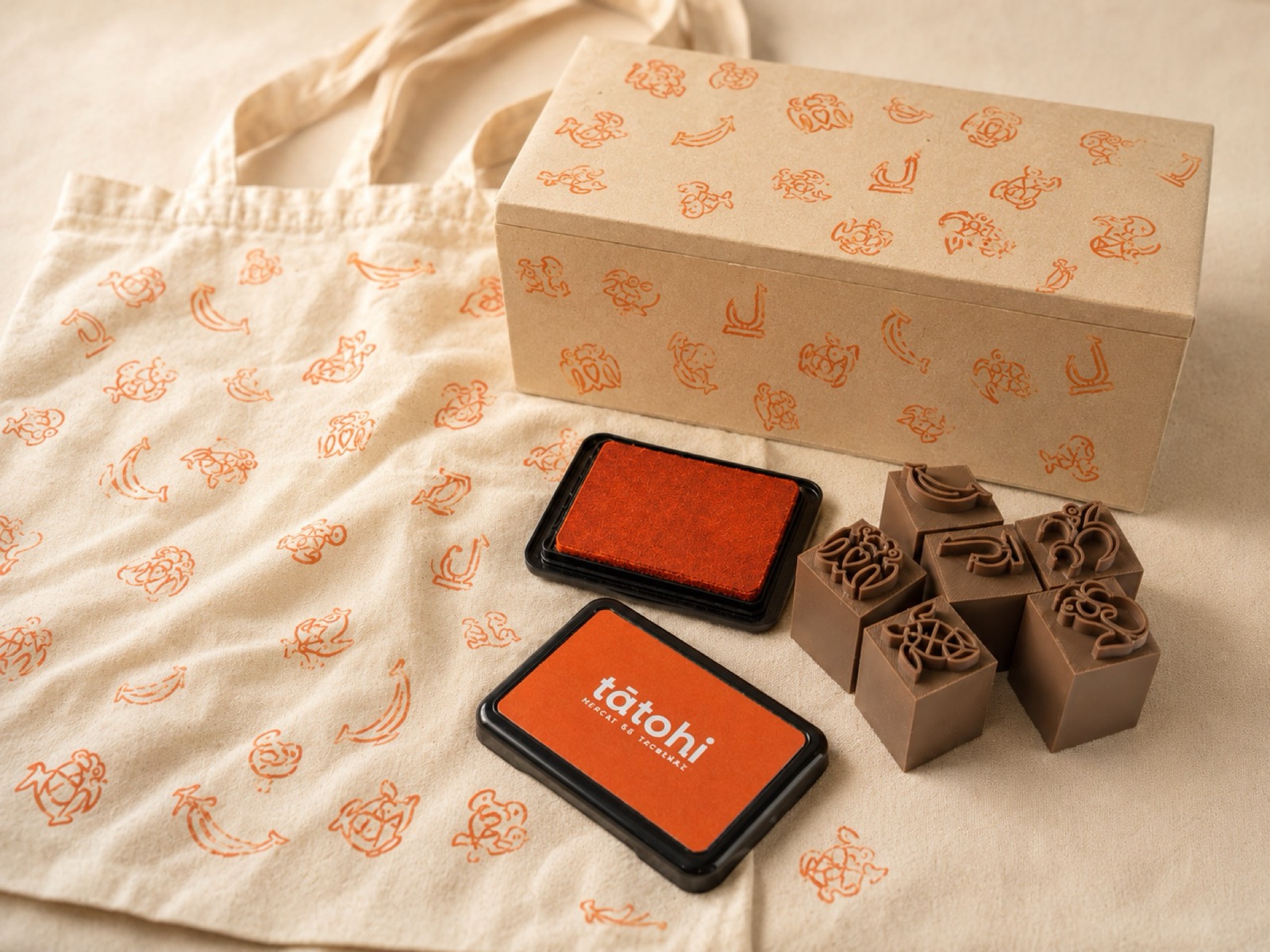 Bolsa de tela estampada con los sellos de Tātohi junto al tampón naranja